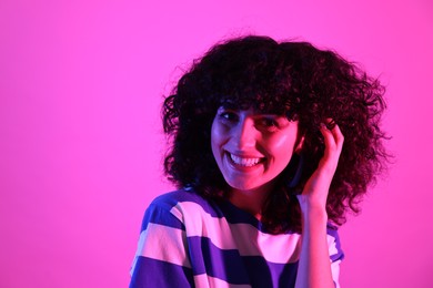 Photo of Beautiful young woman posing on color background in neon lights