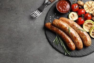 Photo of Flat lay composition with delicious barbecued sausages and vegetables on gray background. Space for text