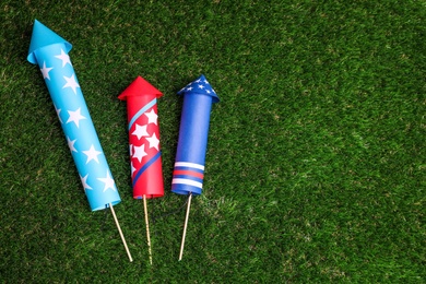 Firework rockets on green grass, flat lay. Space for text