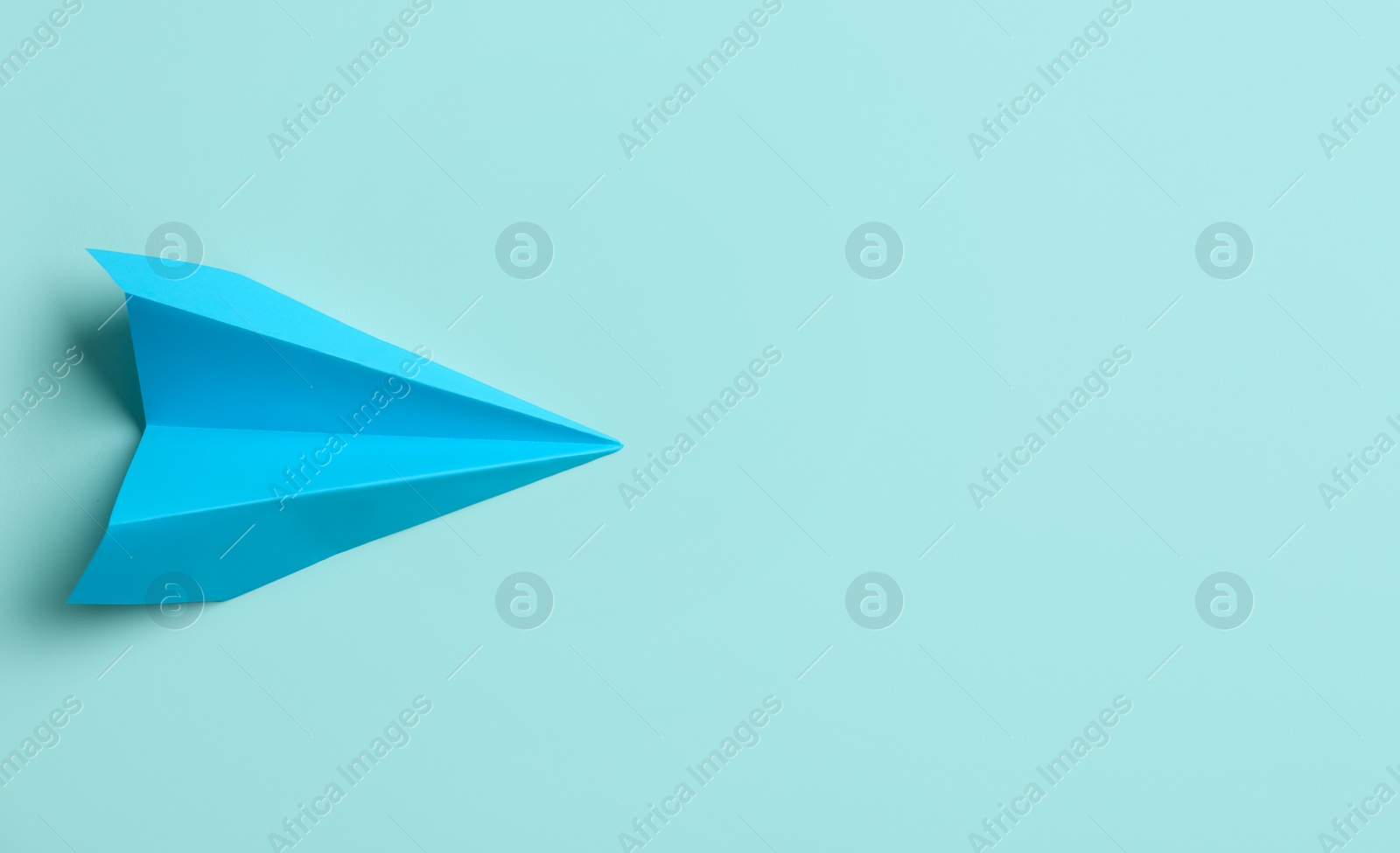 Photo of Paper plane on light blue background, top view. Space for text