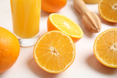 Fresh ripe oranges, juice and reamer on white wooden table