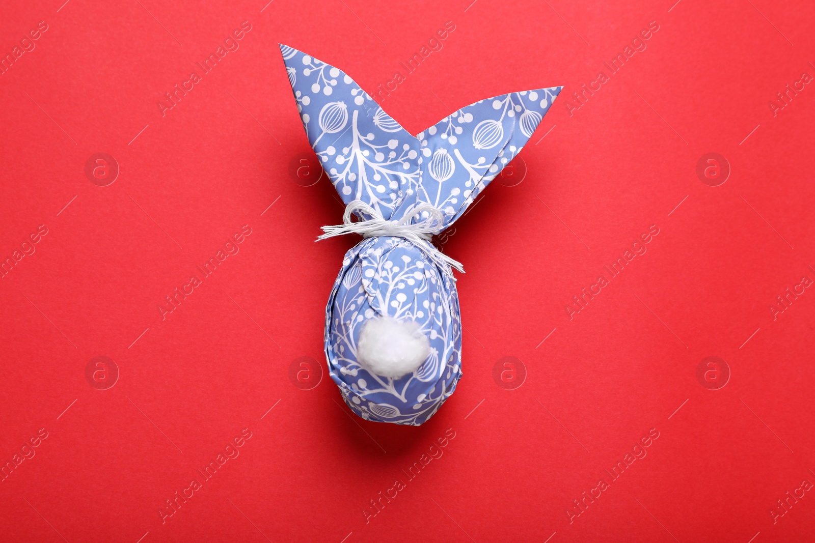 Photo of Easter bunny made of wrapping paper on red background, top view