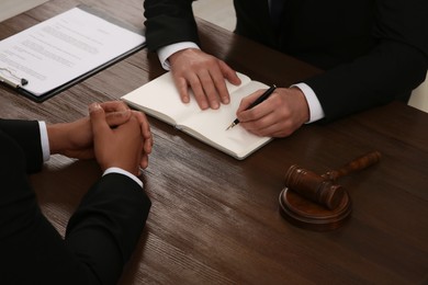 Photo of Law and justice. Lawyers working with documents at wooden table, closeup