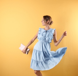 Portrait of young woman in stylish outfit with purse on color background