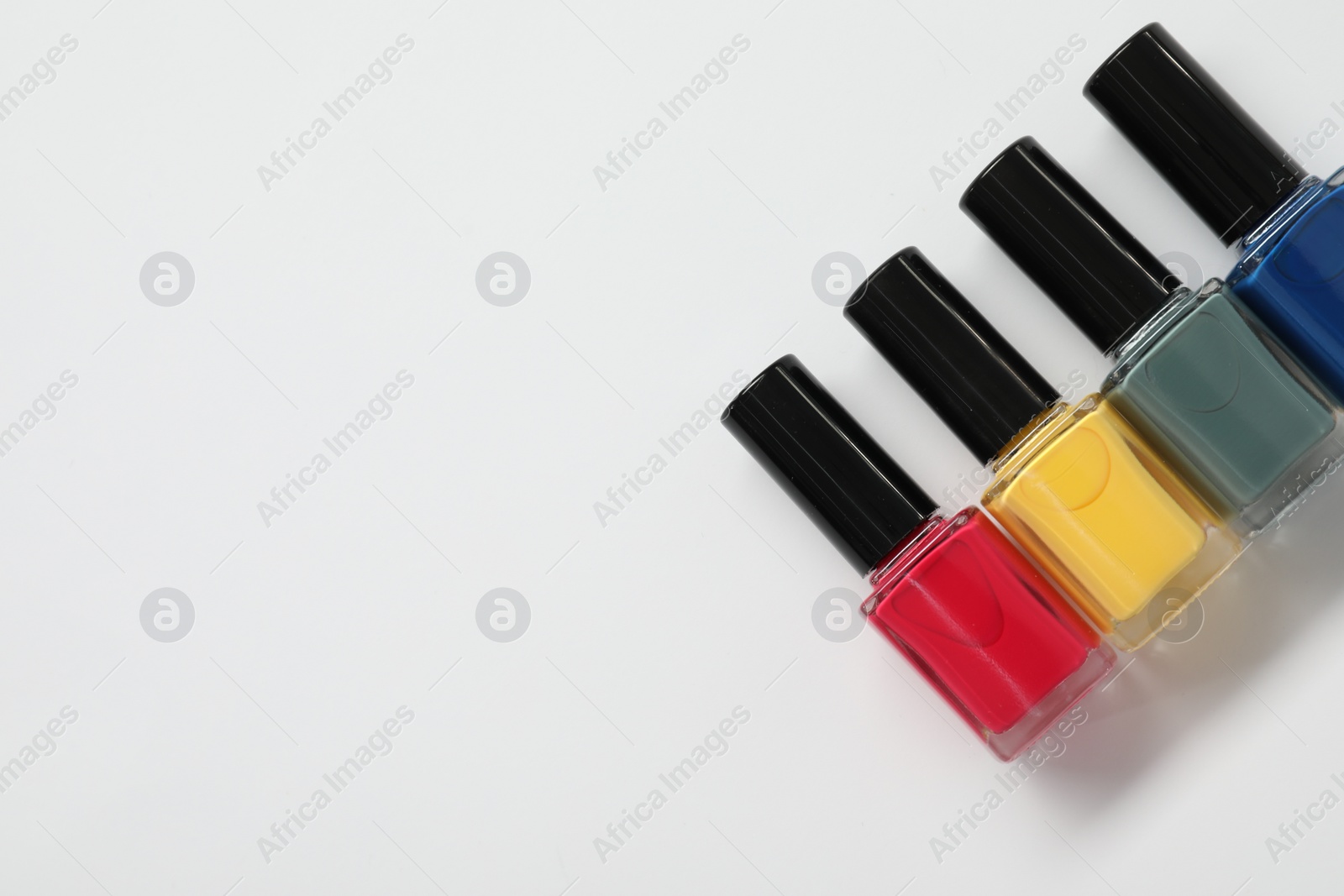 Photo of Nail polishes on white background, flat lay. Space for text