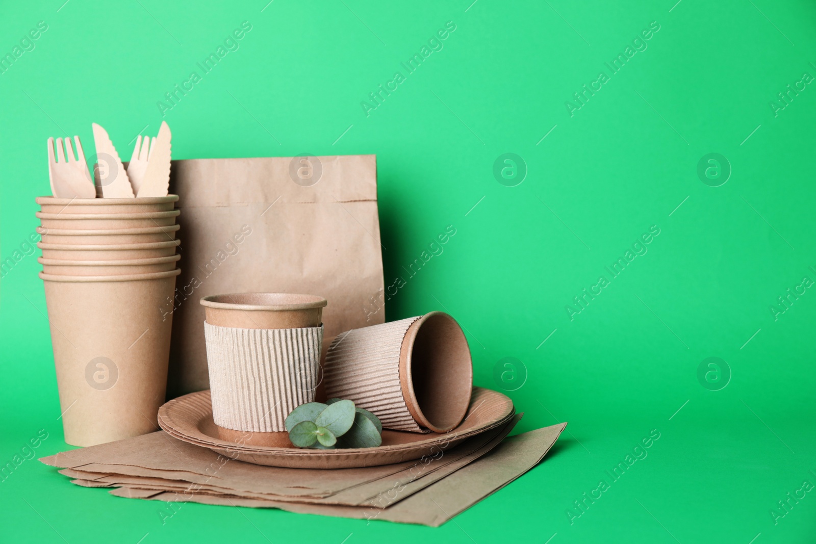 Photo of Set of disposable eco friendly dishware on green background