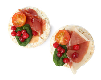 Photo of Puffed rice cakes with prosciutto, berries and tomato isolated on white, top view
