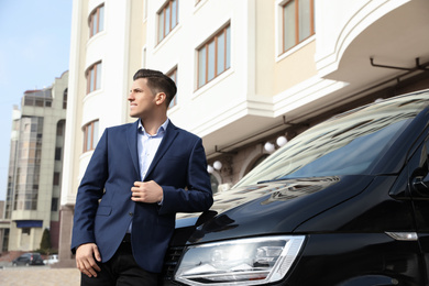 Handsome man near modern car on city street