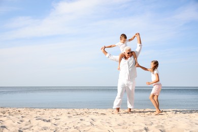 Photo of Cute little children with grandfather spending time together on sea beach