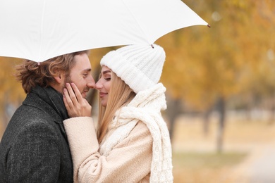 Photo of Young romantic couple with umbrella outdoors on autumn day