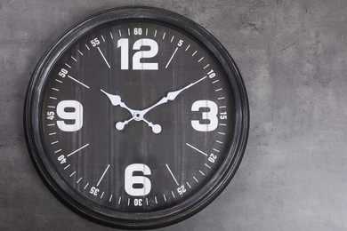 Photo of Stylish analog clock hanging on grey wall