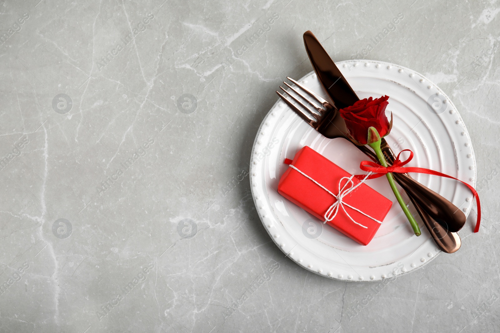 Photo of Beautiful place setting with gift box on light grey table, top view and space for text. Valentine's day romantic dinner