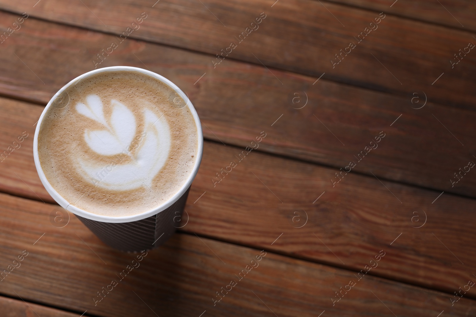 Photo of Coffee to go. Paper cup with tasty drink on wooden table, above view. Space for text