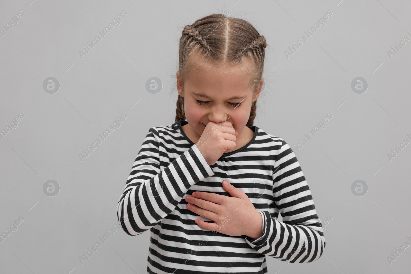 Photo of Sick girl coughing on gray background. Cold symptoms