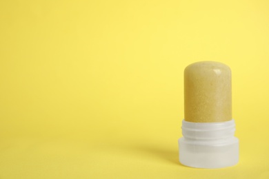 Photo of Natural crystal alum stick deodorant on yellow background. Space for text