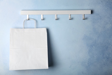 Photo of Rack with paper shopping bag on color wall