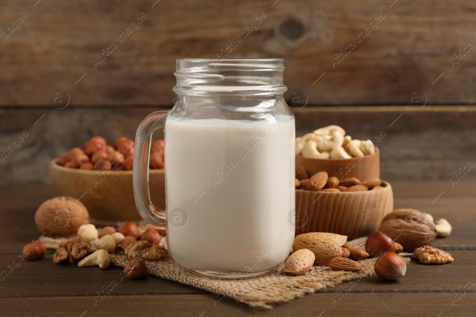 Photo of Vegan milk and different nuts on wooden table