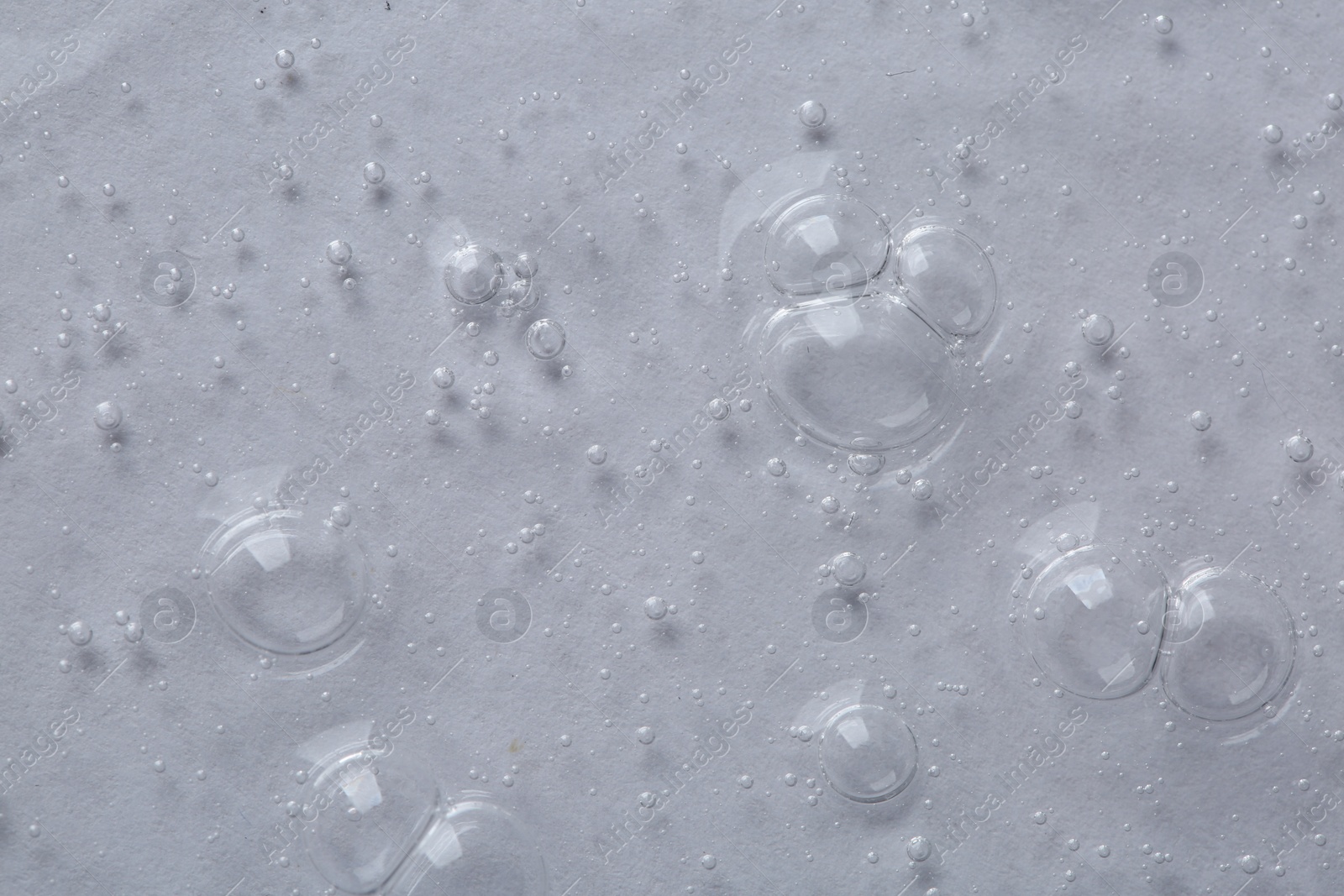 Photo of Clear cosmetic serum on light background, macro view