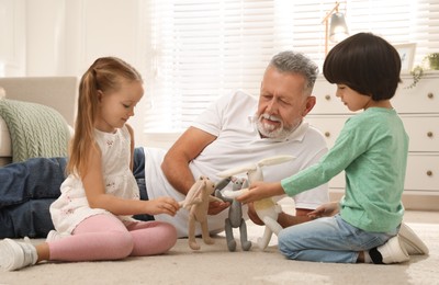 Photo of Happy grandfather and his grandchildren playing with toys together at home
