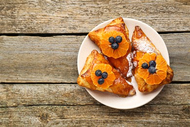 Fresh tasty puff pastry with sugar powder, jam, tangerines and blueberries on wooden table, top view. Space for text