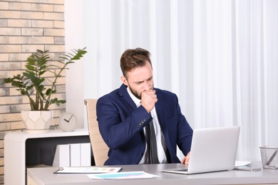Photo of Ill businessman suffering from cough in office