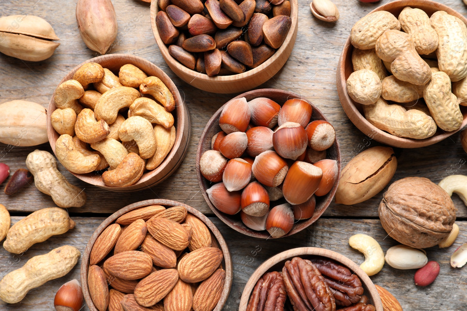 Photo of Flat lay composition with organic nuts on wooden background, top view. Snack mix