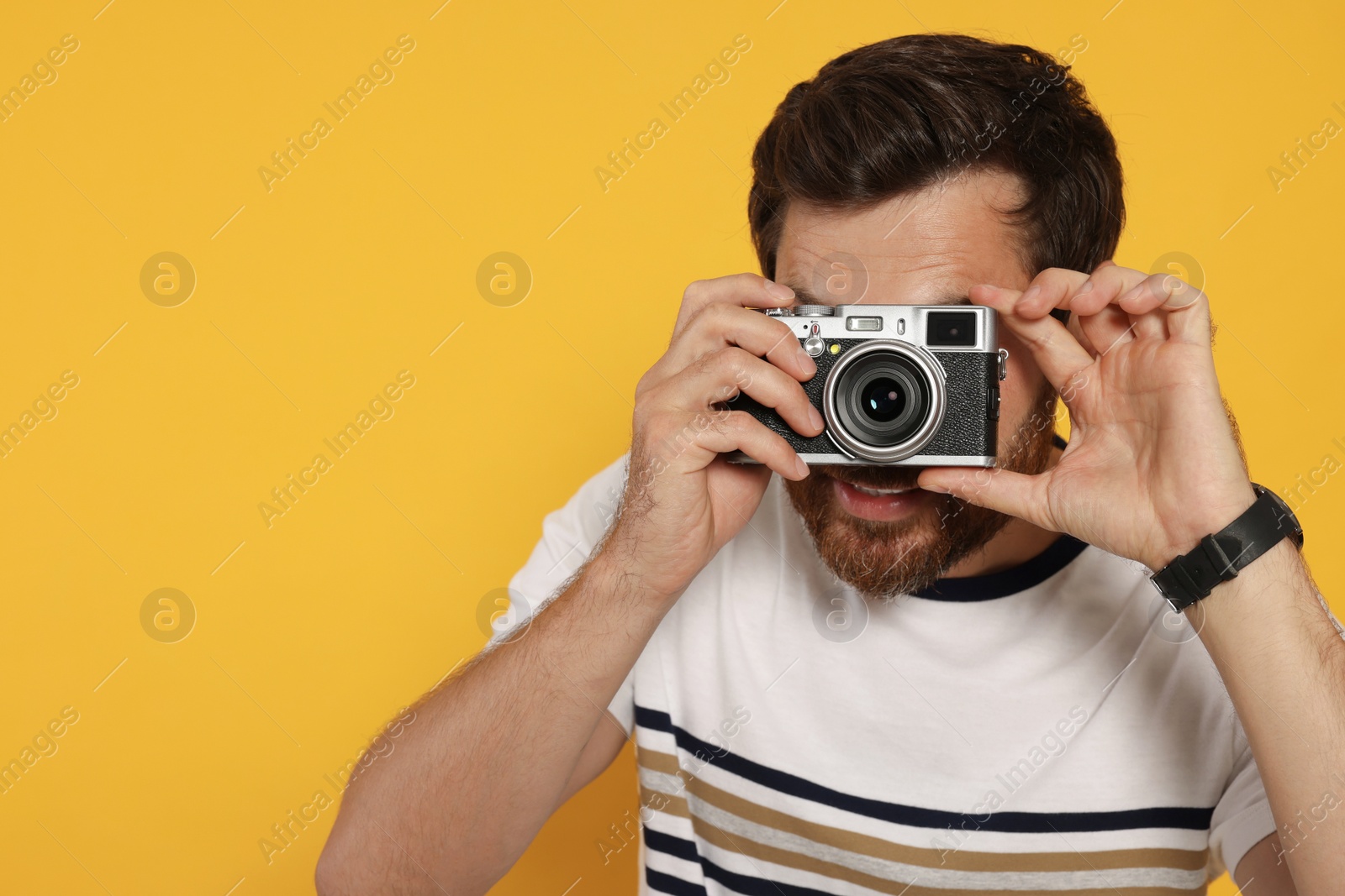Photo of Man with camera taking photo on yellow background, space for text. Interesting hobby