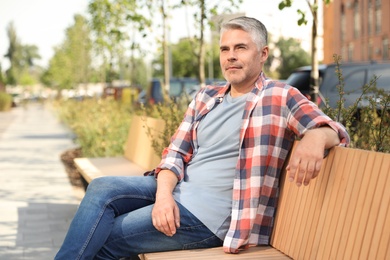 Photo of Handsome mature man on bench in park. Space for text