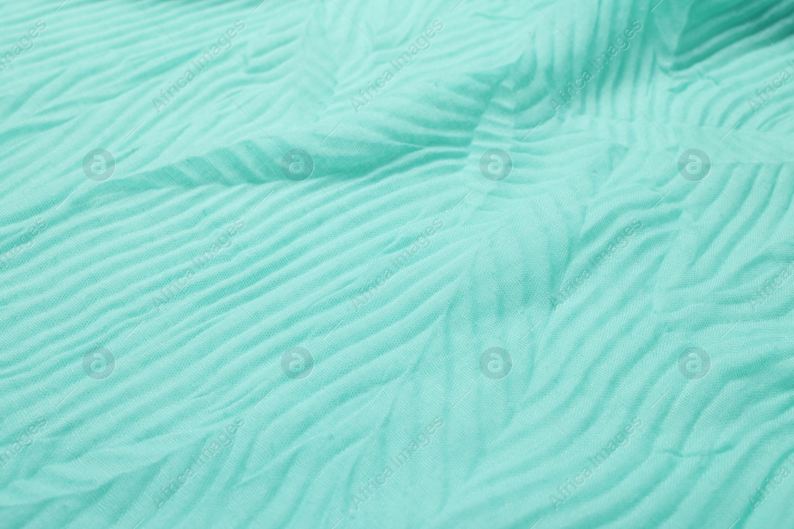 Photo of Texture of turquoise crumpled fabric as background, closeup