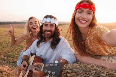 Happy hippie friends taking selfie in field