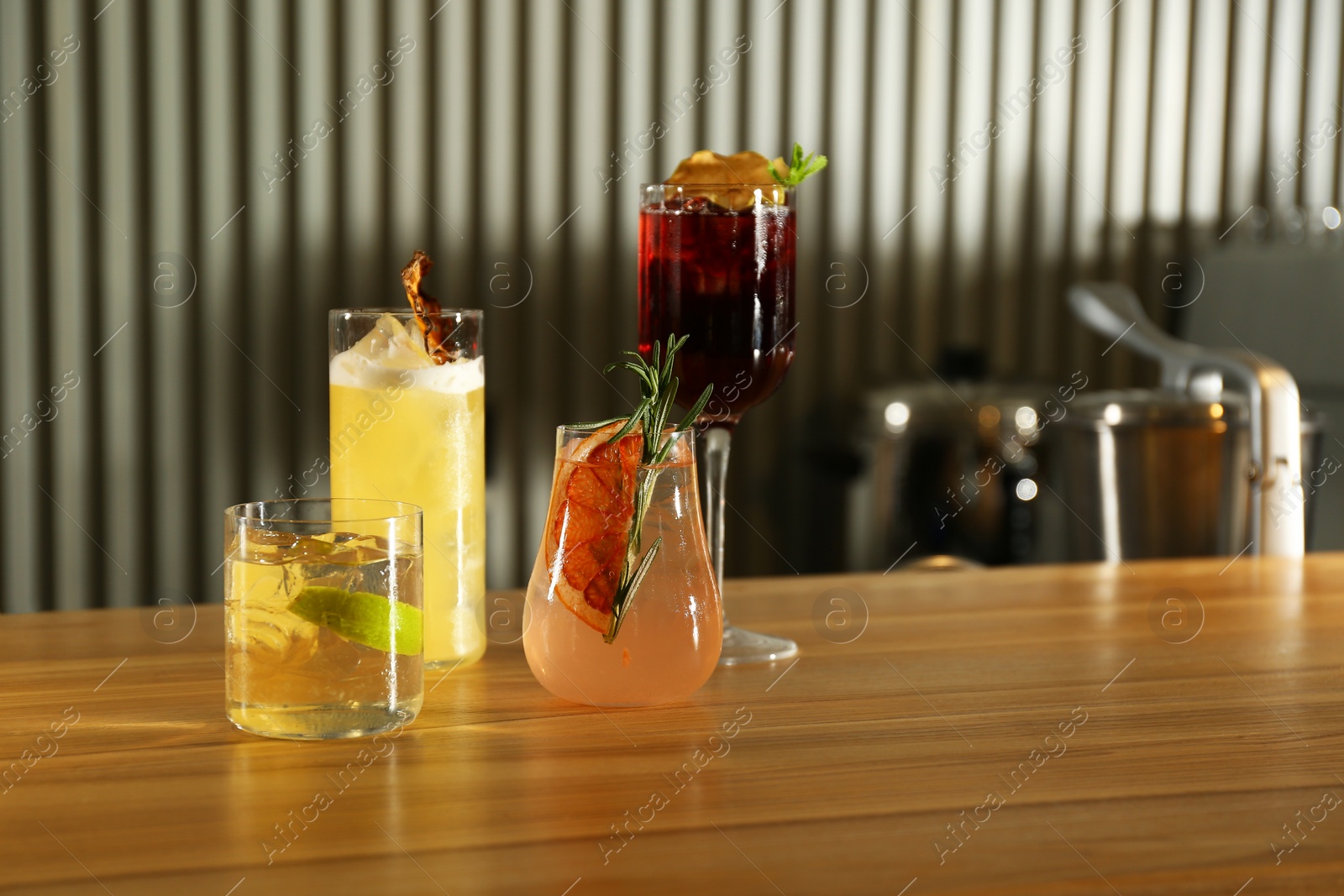 Photo of Glasses of delicious cocktails with vodka on wooden counter in bar