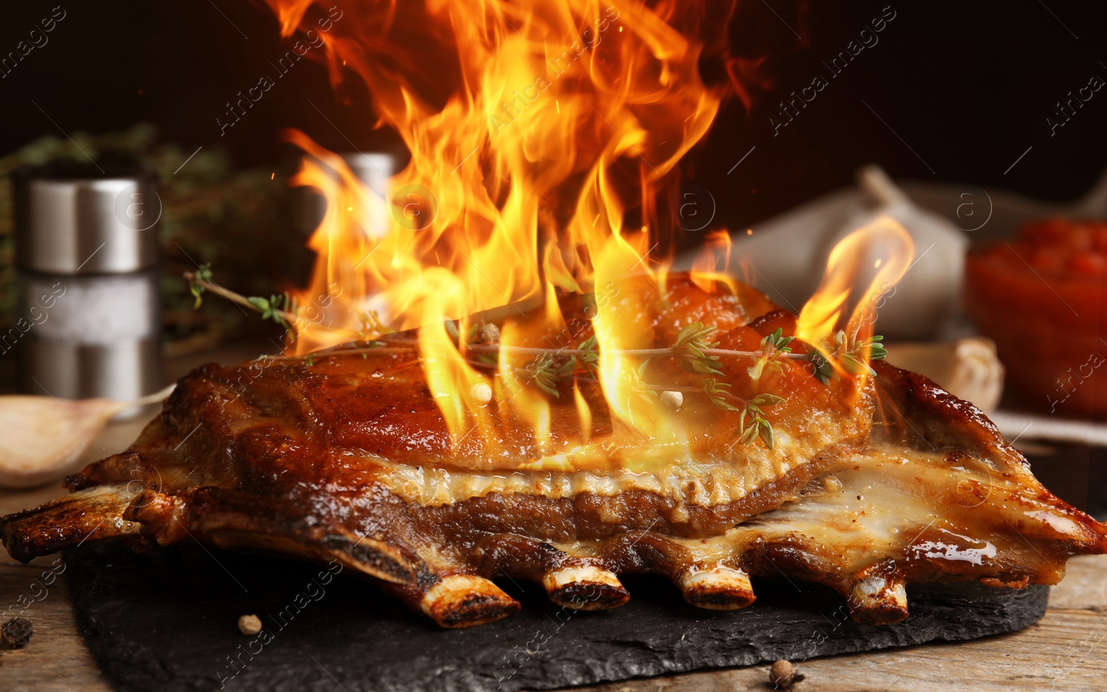 Image of Delicious roasted ribs with flame on table