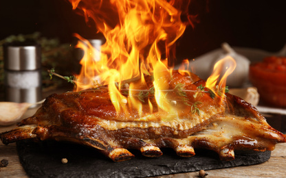 Delicious roasted ribs with flame on table