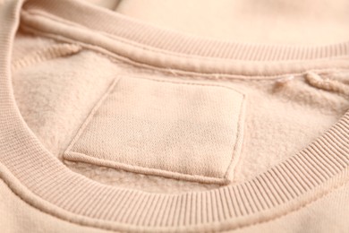 Blank clothing label on beige sweater, closeup