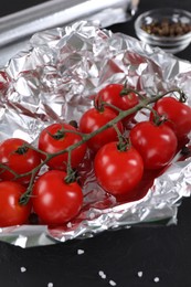 Photo of Tomatoes in aluminum foil on dark table, closeup