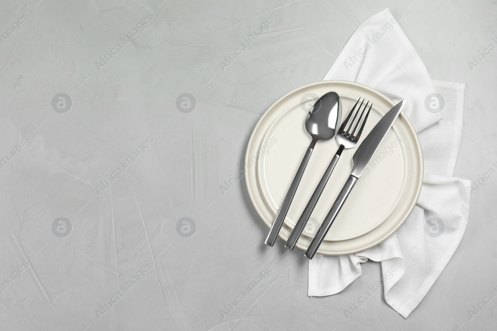 Photo of Stylish setting with elegant cutlery on grey table, top view. Space for text