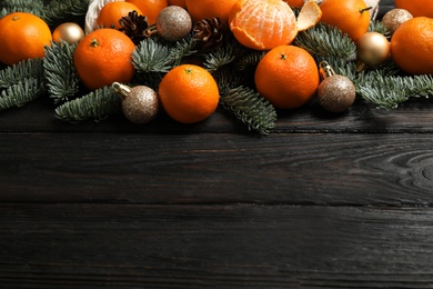 Photo of Christmas composition with fresh tangerines and fir tree branches on dark wooden table, space for text
