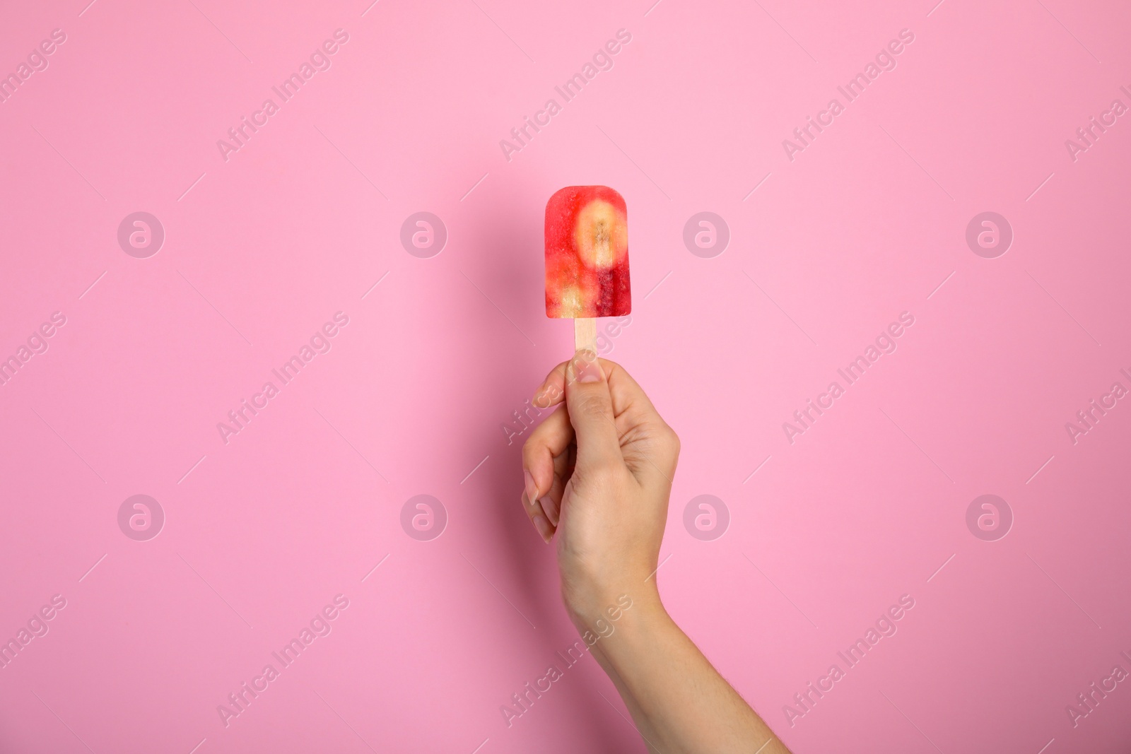Photo of Woman holding berry popsicle on pink background, closeup
