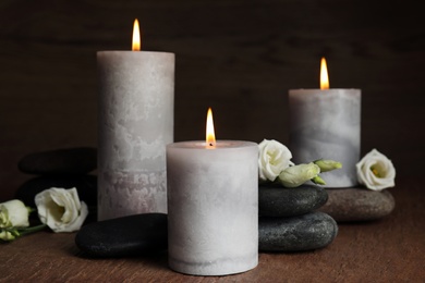 Burning candles, spa stones and flowers on wooden table