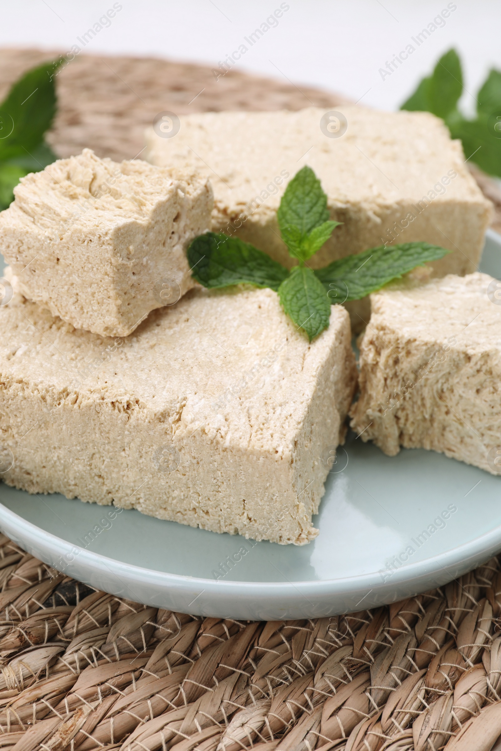 Photo of Pieces of tasty halva and mint on table, closeup