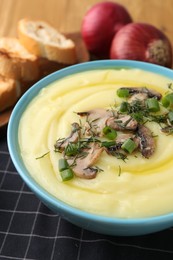 Photo of Bowl of tasty cream soup with mushrooms, green onions and dill on table, closeup