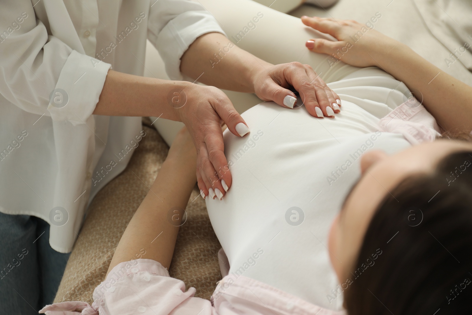 Photo of Doula taking care of pregnant woman at home, closeup. Preparation for child birth