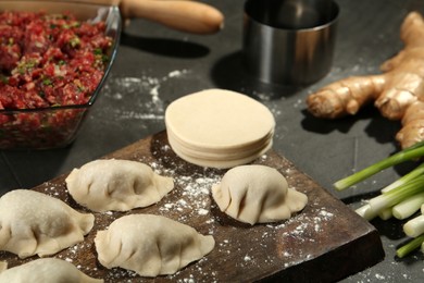 Photo of Uncooked gyoza and ingredients on grey table, closeup