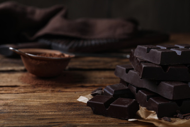 Photo of Tasty dark chocolate bars on wooden table, closeup