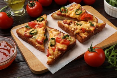 Photo of Tasty pizza toasts and ingredients on wooden table