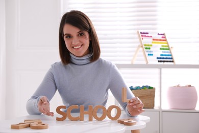 Photo of Happy female English teacher giving lesson indoors. Early childhood education