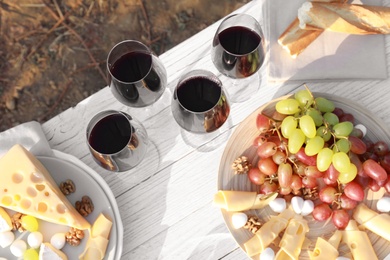 Composition with red wine and snacks on white wooden table, above view