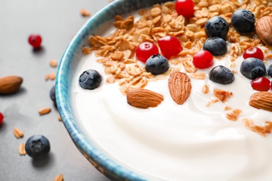 Photo of Bowl with yogurt, berries and granola on table, closeup
