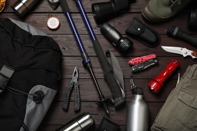 Photo of Flat lay composition with trekking poles and other hiking equipment on wooden background