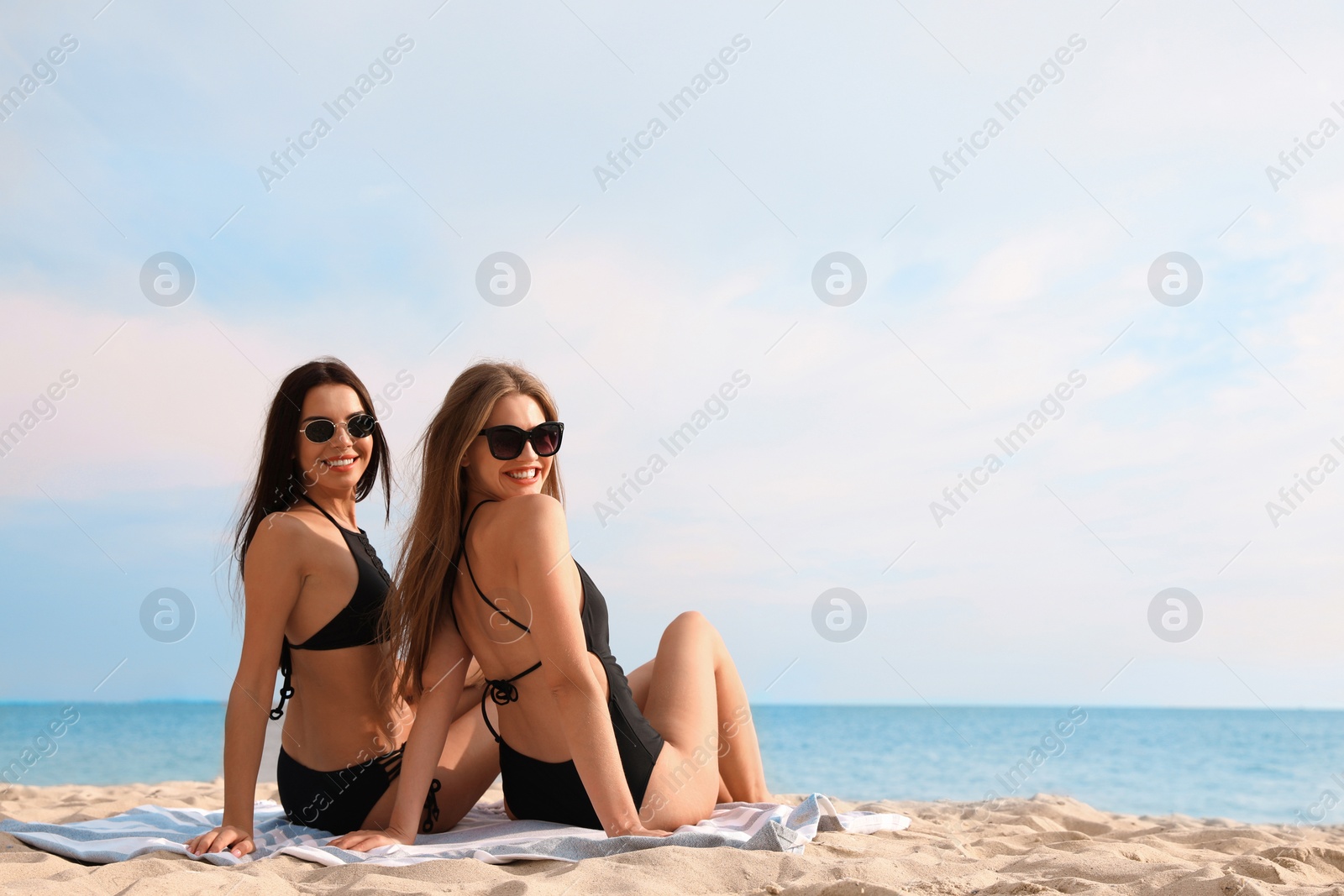 Photo of Young woman in bikini with girlfriend on beach. Lovely couple